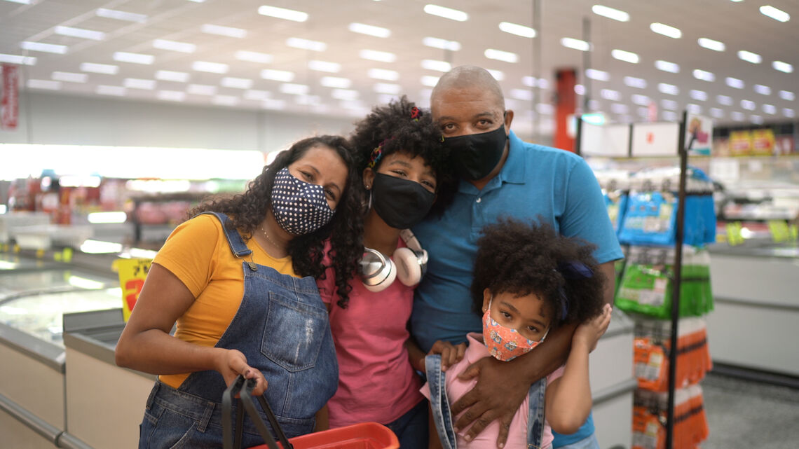 Family of four with two adults, a teen, and a child posing in grocery store