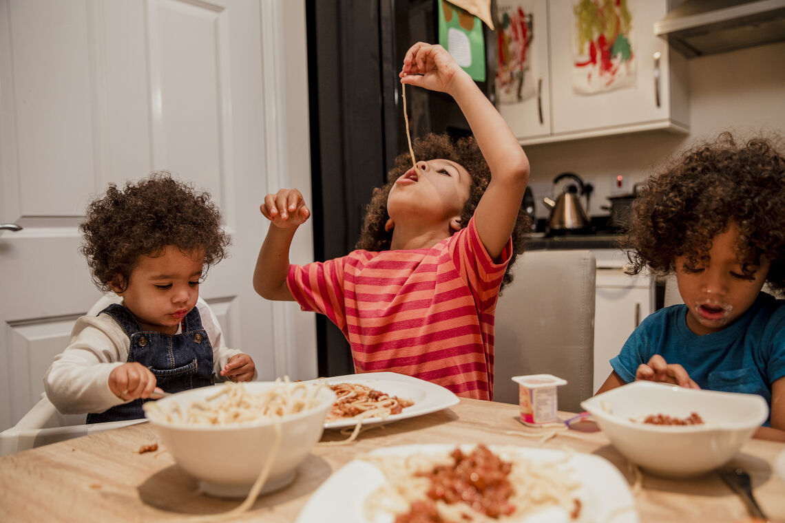 Three children eating pasta